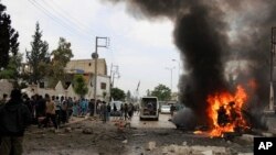 This photo provided by Azaz Media Office, a Syrian anti-government activist group shows Syrian citizens and civil defense workers gathering next of burning car at the explosion scene, in Azaz town, north Syria, May 3, 2017. 