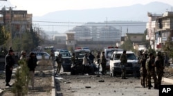 FILE - Afghan security personnel gather at the site of car bomb attack in Kabul, Afghanistan, Nov. 13, 2019.