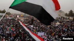 Ribuan pengunjuk rasa melambai-lambaikan bendera Sudan, seraya mengangkat poster dan meneriakkan slogan-slogan dalam sebuah unjuk rasa di depan Kementrian Pertahanan di Khartoum, Sudan 18 April 2019 (foto: Reuters/Umit Bektas)