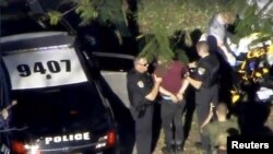 Seorang pria diborgol oleh polisi dekat SMA Marjory Stoneman Douglas seusai insiden penembakan di Parkland, Florida, 14 Februari 2018.