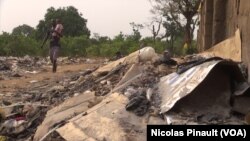 Un père marche avec son fils près des ordures, dans le camp de déplacés de New Kochgoro, à Abuja, le 7 mars 2016.