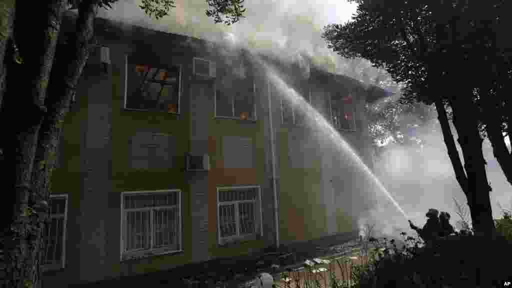 Ukrainian fire fighters put out the fire at the destroyed building after shelling in Donetsk, eastern Ukraine, Aug. 10, 2014. 