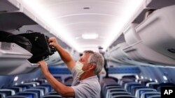 seorang penumpang mengenakan alat pelindung diri di penerbangan Delta Airlines setelah mendarat di Bandara Internasional Minneapolis − Saint Paul, di Minneapolis. (Foto: AP /John Minchillo)