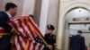 Staff members carry American flags back into the office of the Speaker of the House after they were used as a backdrop while former Speaker of the House Kevin McCarthy spoke after being ousted from the position of speaker on Oct. 3, 2023. 