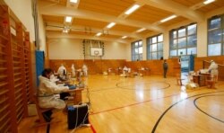 Medical staff members wait for citizens to be tested for coronavirus at a school gym that was set up as a testing facility in Bolzano, northern Italy, Nov. 20, 2020.