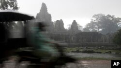 A Cambodian man drives his motor cart past the famed Bayon temple in Angkor complex during the rainy day in Siem Reap province, file photo. 