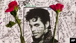 Flowers lay on a T-shirt signed by fans of singer Prince at a makeshift memorial place created outside Apollo Theatre in New York, April 22, 2016.