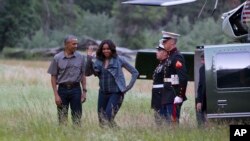 La première dame américaine Michelle Obama, salue quelques personnes de loin, avec à ses côtés le président Barack Obama, après l’arrivée de sa famille à la formation rocheuse Half Dome au parc national Yosemite en Californie, 17 juin 2016. (AP Photo / Ja