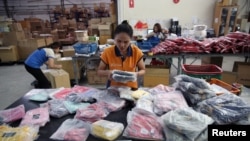 FILE - Workers pack bags with goods imported from China at a company in Bangkok, Thailand, Aug. 7, 2018.