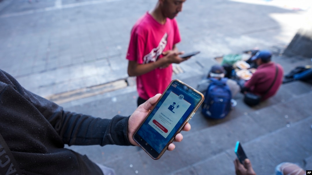 Yender Romero, de Venezuela, muestra la aplicación CBP One en su teléfono celular, que dijo haber usado para solicitar asilo en Estados Unidos y que está esperando una respuesta, en un campamento para migrantes en la Ciudad de México, el lunes 20 de enero de 2025.