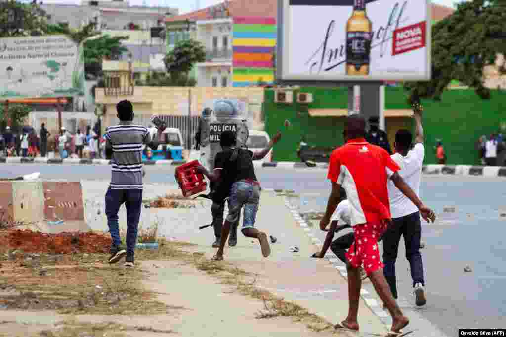 Um manifestante atira uma pedra contra um agente da pol&#237;cia, durante a manifesta&#231;&#227;o anti-governo em Luanda. A pol&#237;cia anti-motim, alguns montados em cavalos, disparou g&#225;s lacrimog&#233;neo e agrediu dezenas de manifestantes que tomaram as ruas da capital angol