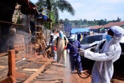 FILE - Ugandan health officials wearing protective gear disinfect the Nakawa open-air market as part of the measures to prevent the spread of the coronavirus disease (COVID-19), in Nakawa division of Kampala, April 17, 2020.