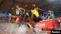 Atlet lari halang rintang Uganda, Benjamin Kiplagat (kanan baju kuning), saat bertanding di Stadion Internasional Khalifa di Doha, Qatar, 1 Oktober 2019. (Foto: Kai Pfaffenbach/Reuters)