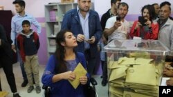 FILE - Using a wheelchair, Lisa Calan, who lost both her legs at an explosion June 5, 2015, in Diyarbakir, in Turkey's predominantly Kurdish southeast during a pro-Kurdish Peoples' Democratic Party's, (HDP) rally for the previous elections, casts her vote Sunday, Nov. 1, 2015. 