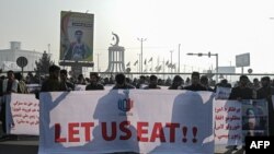 আফগানিস্তানের রাজধানী কাবুলের রাস্তায় একটি বিক্ষোভ চলাকালীন গভীর অর্থনৈতিক সংকটের সাথে লড়াই করা লোকেরা 'আমাদের খেতে দিন' লেখা একটি ব্যানার ধরে রেখেছে। ২১শে ডিসেম্বর, ২০২১। 