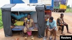 FILE - Truck drivers rest as trucks carrying food, humanitarian aid and industrial equipment wait due to sanctions imposed by Niger's regional and international allies, in the border town of Malanville, Benin August 18, 2023.
