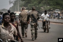 FILE - French army military instructors walk on one of the main roads in Tanguietan, northern Benin, March 28, 2022.