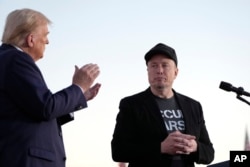 FILE - Republican presidential nominee former President Donald Trump, left, claps as Tesla and SpaceX CEO Elon Musk prepares to depart after speaking at a campaign event at the Butler Farm Show, on Oct. 5, 2024, in Butler, Pa.