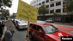 Members of the San Francisco Taxi Workers Association carry signs at a rally at Uber headquarters in San Francisco, California, June 22, 2015. The taxi drivers, contracted by Uber, wanted employee status and benefits.