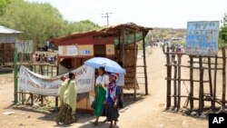 FILE - People walk past a checkpoint in northwestern Ethiopia next to the border with Sudan, June 3, 2015. Sudan and Ethiopia agreed Tuesday to deploy joint forces to secure their border. 