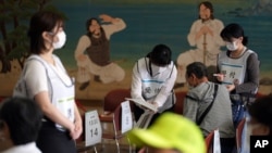 24일 일본 도쿄에 설치된 신종 코로나바이러스 백신 접종 장소에서 관계자들이 접종 희망자의 체온을 재고 있다.