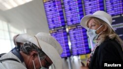 Los viajeros en Europa han comenzado a protegerse contra el coronavirus, como esta mujer holandesa y su amigo británico en el aeropuerto de Barcelona, España, el 26 de febrero de 2020.