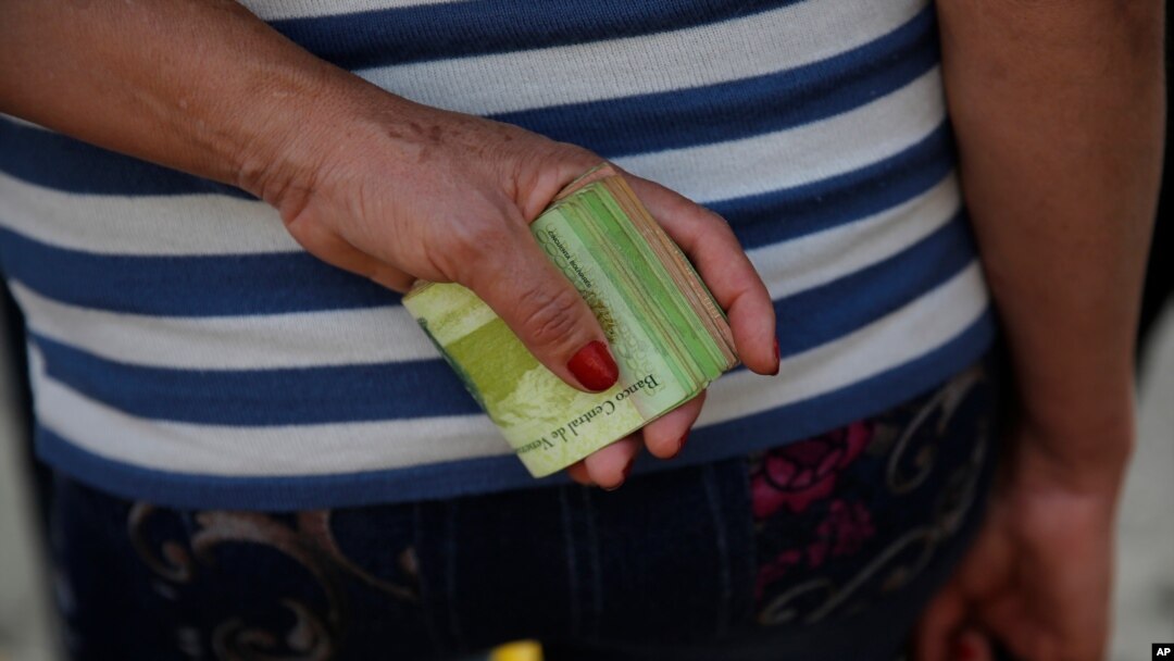 Una mujer sostiene un gran fajo de billetes para pagar un pasaje de autobús en Caracas, el 7 de febrero de 2018.