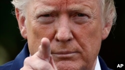 President Donald Trump points to a reporter for a question on the South Lawn of the White House before departing, July 19, 2019, in Washington. 