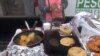 A vendor in Los Angeles, Calif., prepares pupusas, center, and other savory Salvadoran street food. The city council unanimously voted to decriminalize sidewalk sales. (A. Martinez/VOA)