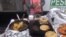 A vendor in Los Angeles, Calif., prepares pupusas, center, and other savory Salvadoran street food. The city council unanimously voted to decriminalize sidewalk sales. (A. Martinez/VOA)