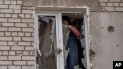 ARCHIVO - Una mujer coloca plástico sobre su ventana dañada después de un ataque ruso la noche anterior, en la zona residencial de Mikolaiv, Ucrania, el 29 de marzo de 2022. AP