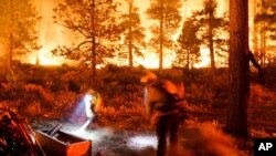 Two firefighters create a fuel break as the Caldor Fire burns near homes in South Lake Tahoe, Calif., Aug. 30, 2021.