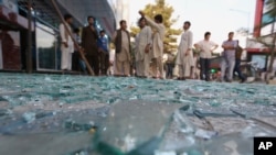 After a bomb explodes in a central business district of Kabul, Afghanistan, onlookers gather at the scene, July 13, 2015.