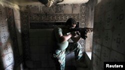 A Free Syrian Army fighter aims his weapon as he takes position inside a house in the city of Aleppo July 11, 2013. 