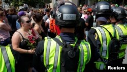 Police in riot gear block demonstrators at the site where Heather Heyer was killed, on the one year anniversary of 2017 Charlottesville "Unite the Right" protests, in Charlottesville, Virginia, Aug. 12, 2018. 
