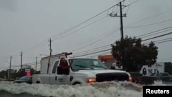 A car passes through a flooded street as Tropical Storm Imelda hits Houston, Sept. 19, 2019, in this screen grab obtained from social media video.