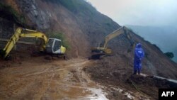 A worker looks at heavy equipment used to clear debris and soil after a mountainside eroded due to heavy rains brought about by Typhoon Goni, along Kennon Road, a main road leading into the Philippine city of Baguio, Aug. 22, 2015. 