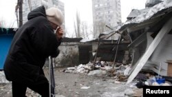 A woman reacts as she stands at a market that, according to locals, was recently damaged by shelling, in Donetsk, eastern Ukraine, Jan. 19, 2015. 