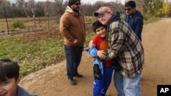 Caroline Clarin, right, hugs Haiwad Massoodi on a visit by his father, Sami, rear left, and Sami Massoodi's cousin Ihsanullah Patan, right, and Patan's son, Ali, at her farm in Dalton, Minn.Oct. 30, 2021.