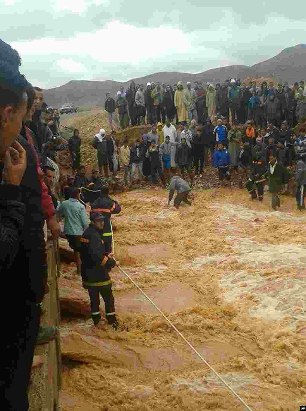 Cette image prise avec un téléphone portable montre pompiers marocains tirant une corde dans une tentative de sauver les habitants de Guelmim, au sud ouest du Maroc, bloqués par la crue des eaux, lundi 24 novembre 2014.