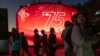 FILE - Visitors to a mall pass by a screen celebrating China's 75th National Day in Beijing, Oct. 2, 2024. 