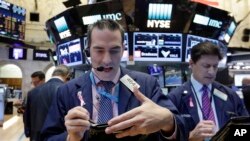 Trader Gregory Rowe, left, works on the floor of the New York Stock Exchange, Nov. 21, 2016. 