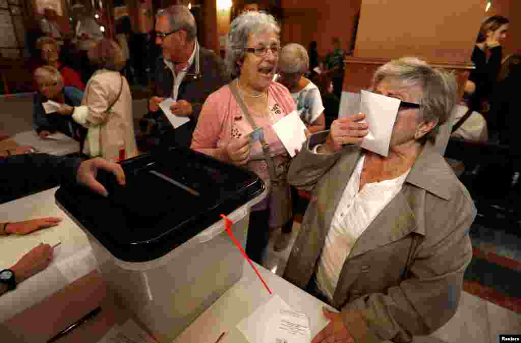 Una mujer besa una papeleta antes de depositar su voto en una mesa electoral para el referéndum de independencia prohibido en Barcelona, ​​España, el 1 de octubre de 2017. 