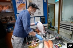 A staff member holds a flounder from Fukushima at Sakana Bacca, a seafood retailer, on Oct. 31, 2023, in Tokyo. (AP Photo/Eugene Hoshiko)