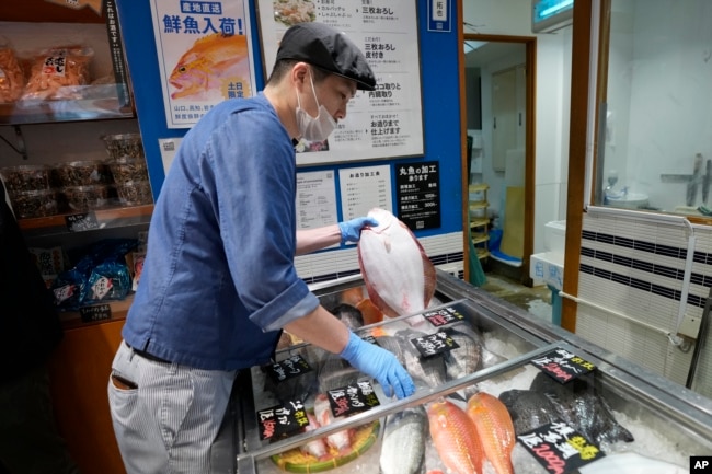 A staff member holds a flounder from Fukushima at Sakana Bacca, a seafood retailer, on Oct. 31, 2023, in Tokyo. (AP Photo/Eugene Hoshiko)