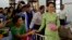Myanmar's opposition leader Aung San Suu Kyi, center, greets a patient in a bed at Yangon General Hospital in Yangon, Myanmar, Oct. 30, 2015. 