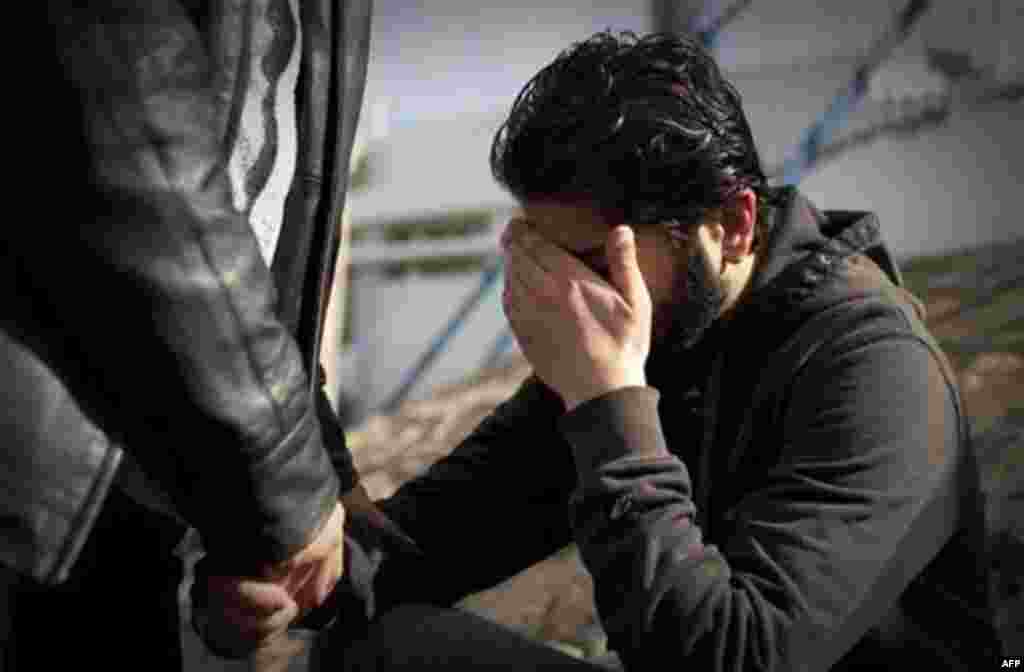 A Libyan man reacts after identifying his killed brother at the morgue of the Jalaa hospital in Benghazi, eastern Libya, Saturday, March 19, 2011. Explosions shook the Libyan city of Benghazi on Saturday while a fighter jet was heard flying overhead, and 