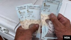Un hombre sostiene los devaluados billetes venezolanos