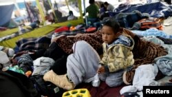 A child traveling with a caravan of migrants from Central America sits at a camp near the San Ysidro checkpoint, after U.S. border authorities allowed the first small group of women and children entry from Mexico overnight, in Tijuana, Mexico, May 1, 2018.