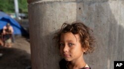 En la foto de archivo una niña hondureña quien espera el desayuno cocinado por su familia debajo de un puente en las afueras de San Pedro Sula, Honduras, el lunes 11 de enero de 2021.